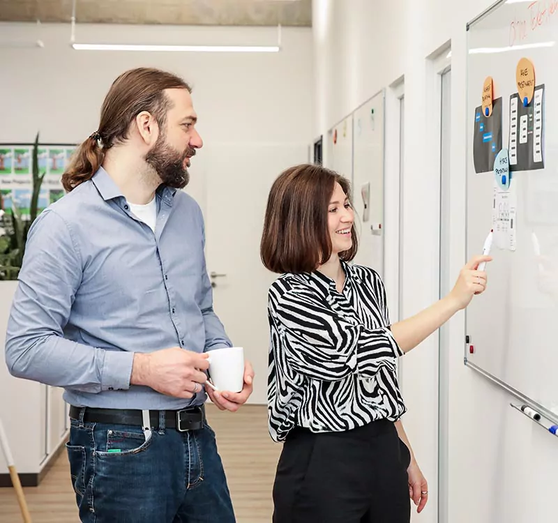 Gregor und Yana besprechen Projekte am Whiteboard